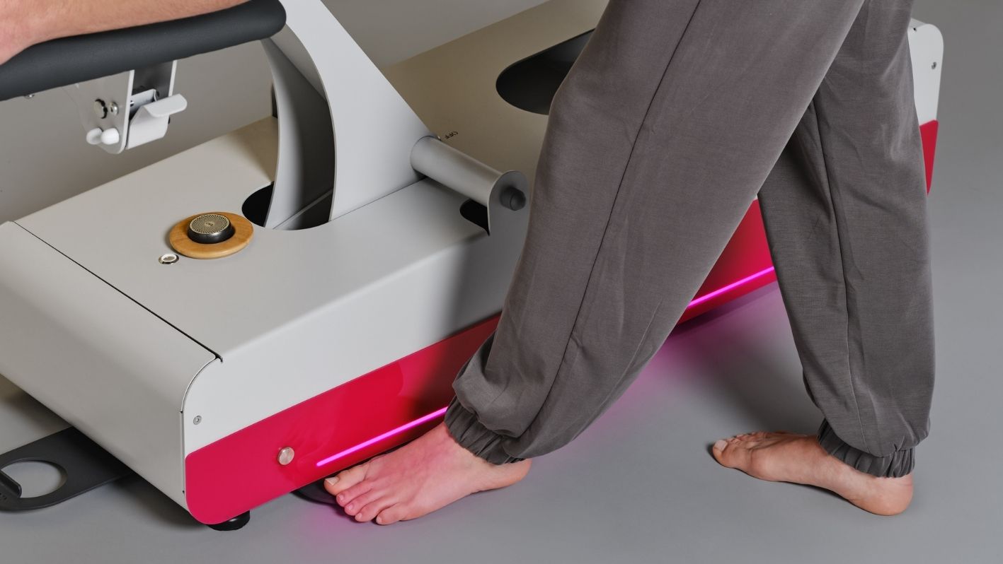 Mann bedient barfuß die Fußpedale der 5-teiligen Physio-Therapieliege SWOP 5 Pro von naggura