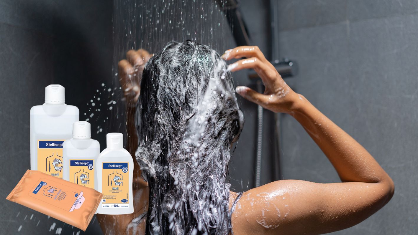 Frau wäscht sich unter der Dusche die Haare, im Vordergrund die Stellisept med Produkte